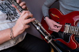 två personer spelar instrument, till vänster en klarinett och till höger gitarr