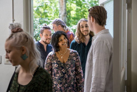 cirkelledare välkomna cirkeldeltagare. En har redan kommit in i lokalen, fyra är på väg in.