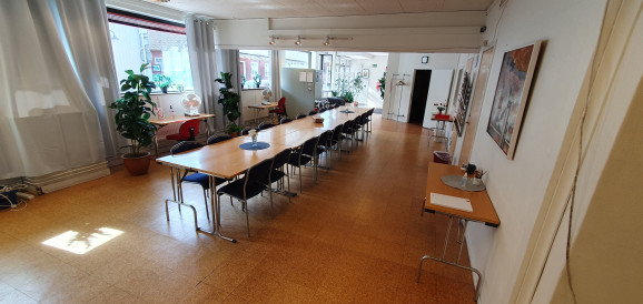 Stort rum med långt bord centralt placerat med 20 stolar runt sig.