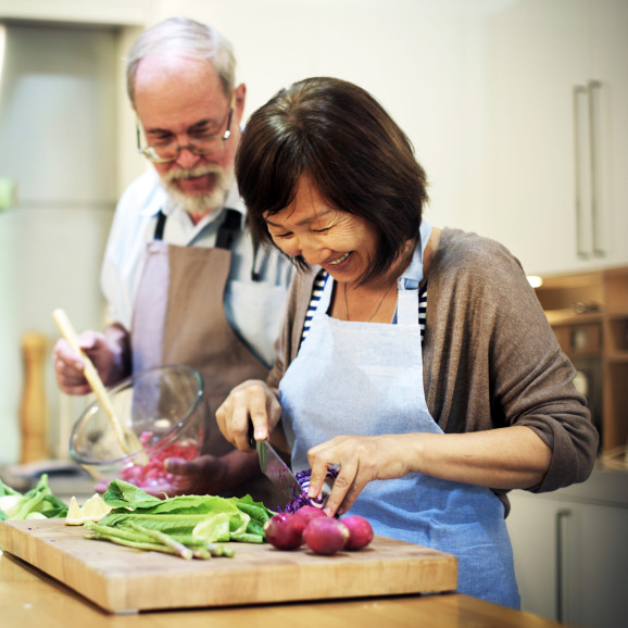 ett äldre par, en man och en kvinna, lagar mat tillsammans