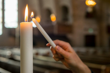 en hand tänger ett större ljus med ett mindre ljus