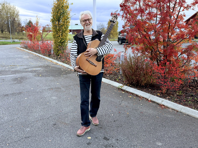 Anders Hedén utanför Hackås Föreningshus med sin gitarr i famnen.
