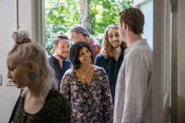 cirkelledare välkomna cirkeldeltagare. En har redan kommit in i lokalen, fyra är på väg in.