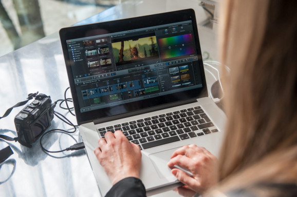 person sitter framför laptop och arbetar i redigeringsprogram