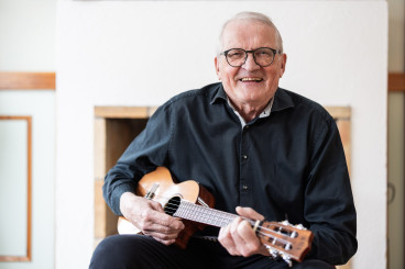 Torbjörn Jonsson med ukulele i i svart skjorta sitter ner