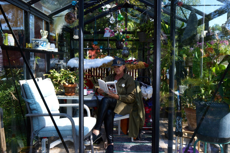 Py Bäckman sitter inne i ett växthus omgiven av grönska