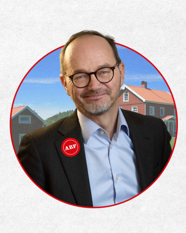 Tomas Eneroth i förgrunden mot två röda hus mot blå himmel.