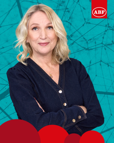 Annica Dahl ler lite och håller armarna i kors framför en turkos bakgrund. Används till verksamhetsberättelsen 2024