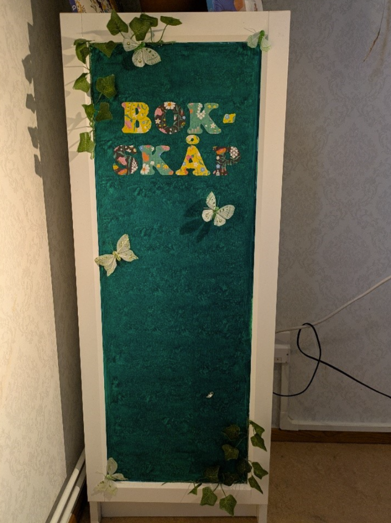 Litet skåpbibliotek på en arbetsplats i en persons hem.