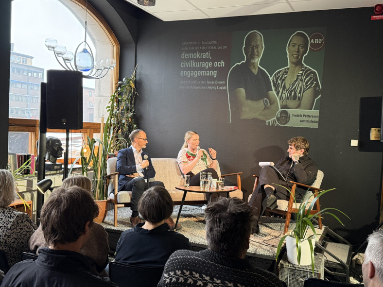 Ett samtal mellan tre personen uppe på en liten scen framför en sittande publik