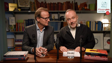 Eric Sundström, chefredaktör för Fönstret och Lars Strannegård, rektor för Handelshögskolan sitter vid ett bord med mikrofoner. Eric tittar in i kameran och ler, Lars tittar på Eric. De pratar i första avsnittet av Fönsterplats podcast.