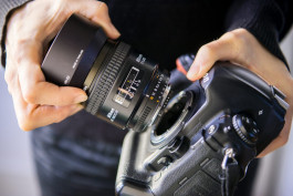 en person håller en systemkamera i handen och har tagit ut objektivet