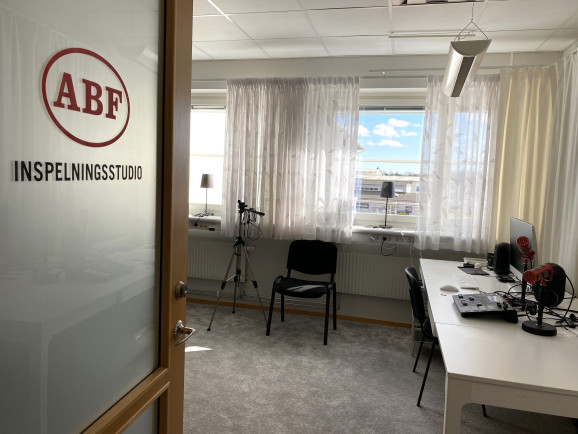 en studio med heltäckningsmatta och skrivbord med teknik för inspelning.