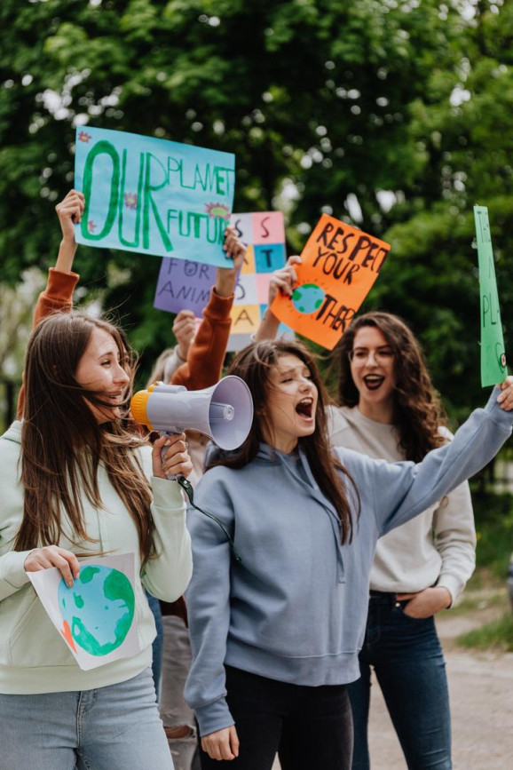 flera unga tjejer ropar i megafon och håller i handskrivna skyltar, där det bland annat står: our planet future